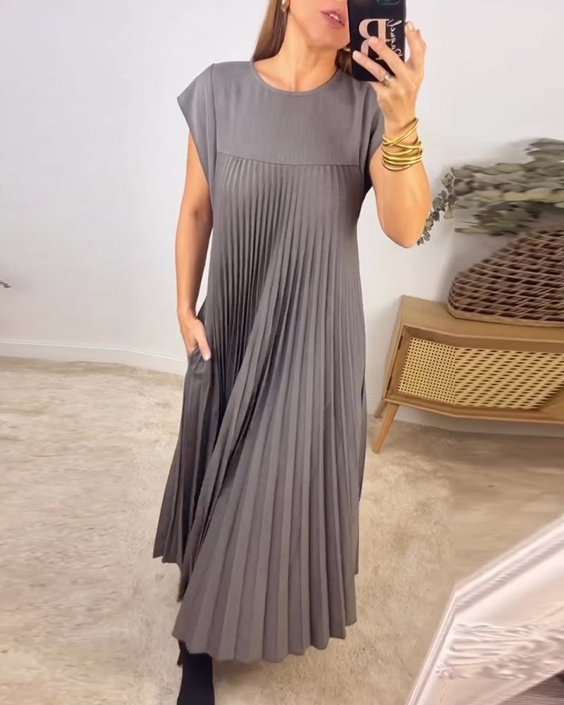 Side profile of the Fern pleated maxi dress showing the elongated silhouette in beige