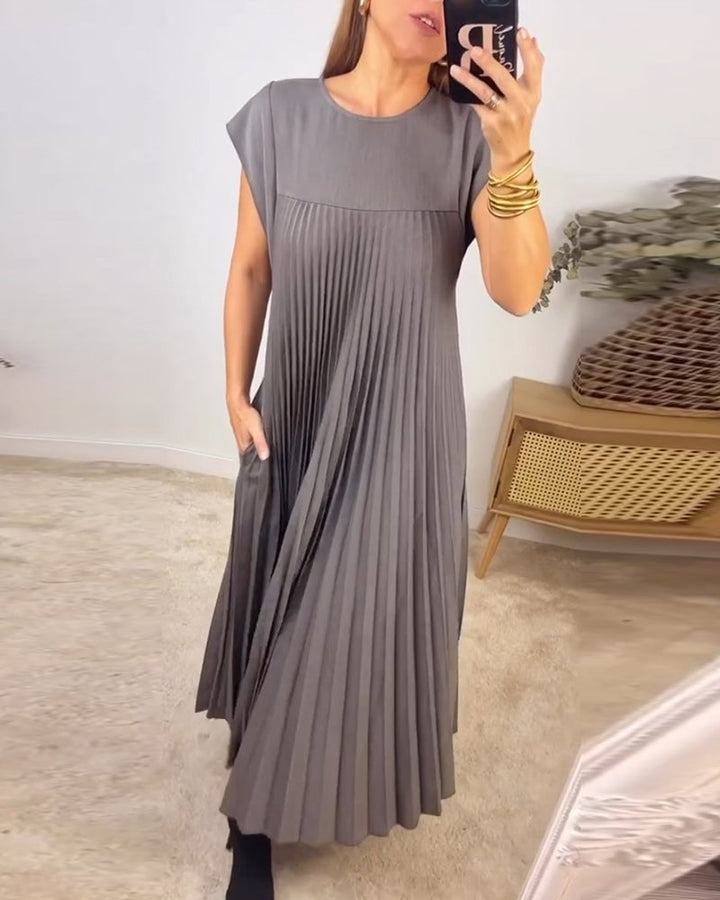 Side profile of the Fern pleated maxi dress showing the elongated silhouette in beige