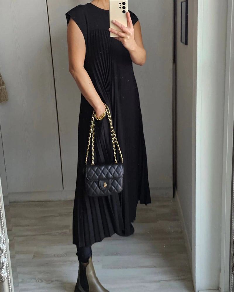 Lifestyle shot of the Fern pleated maxi dress in brown worn at a daytime occasion
