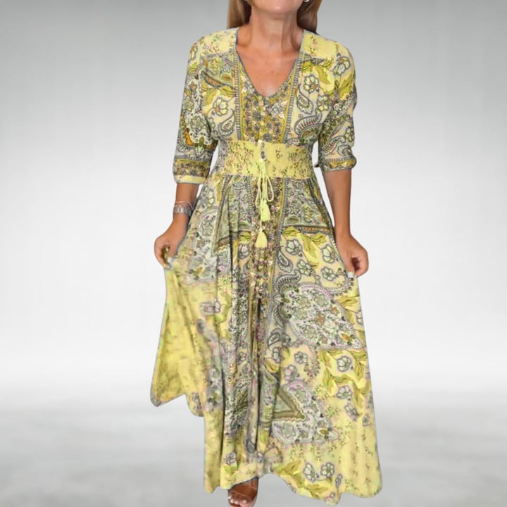 Lifestyle shot of the Flora draped maxi dress in yellow worn outdoors in a bright natural setting