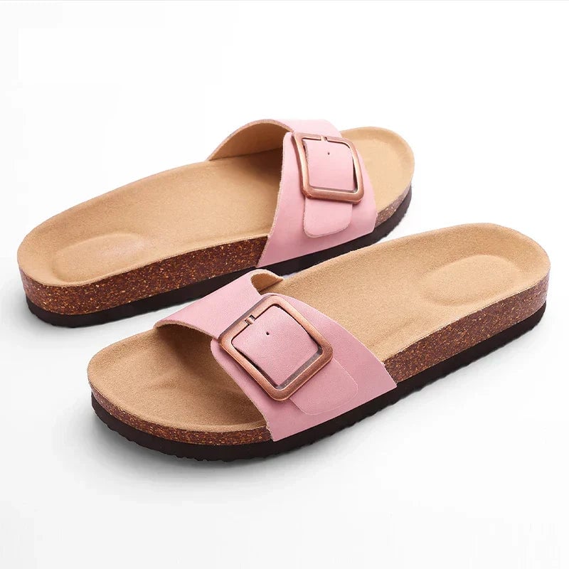 Flora flat sandals in beige displayed at an angle to highlight the polished buckle accent