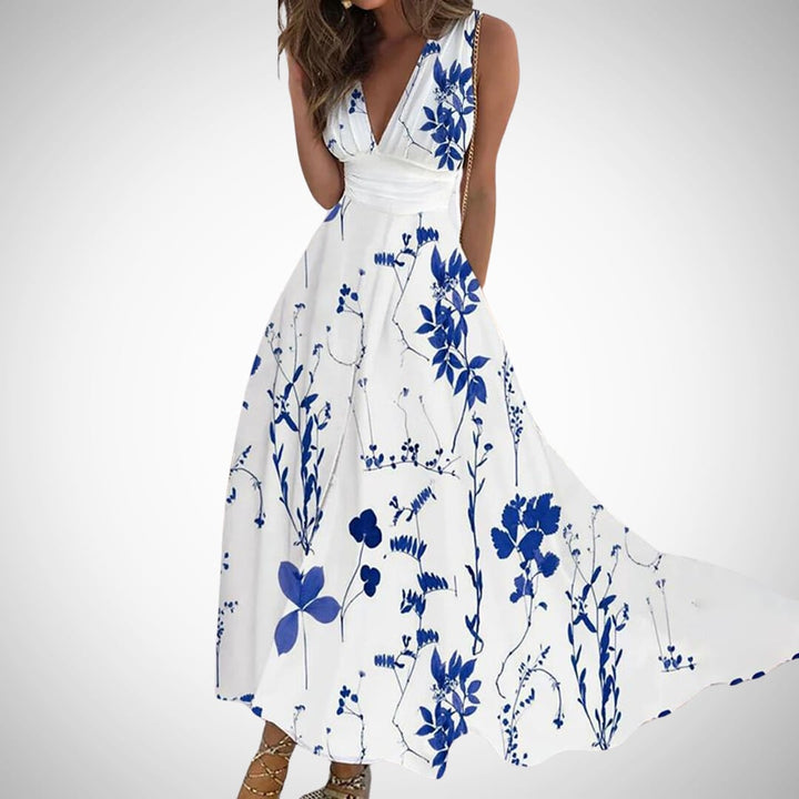 Woman wearing the Flora sleeveless floral maxi dress with a deep V-neckline and ruched wrap waist in white and blue botanical print