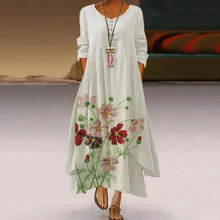 Woman wearing a white floral print long sleeve loose maxi dress with botanical hem design, front view