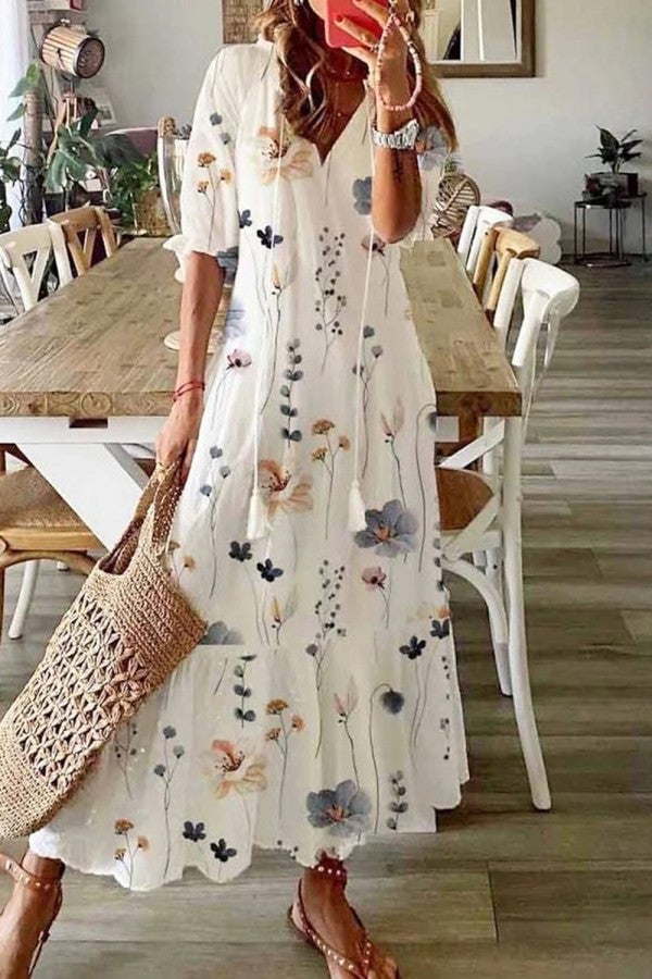 Woman wearing a watercolor floral print V-neck tassel maxi dress with ruffled hem and 3/4 flounce sleeves in floral white