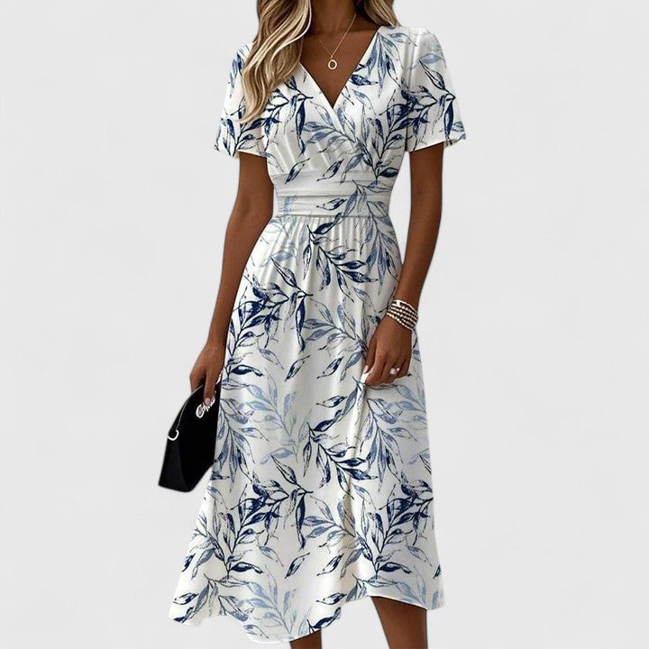Close-up detail of the Flora midi dress showing the navy botanical leaf print, flutter sleeve, and gathered waist on a white fabric base