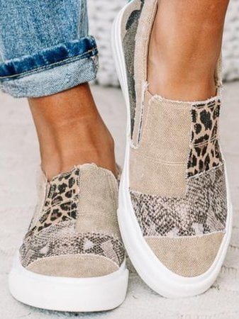 Frances slip-on shoes in khaki worn by a woman walking on a city sidewalk