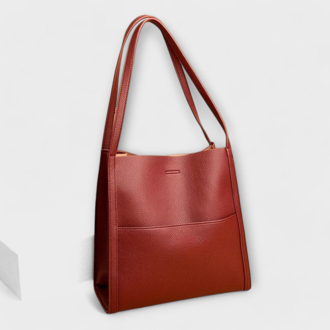 Freydis structured handbag in a clean minimalist silhouette, shown in a neutral setting highlighting its spacious design and shoulder straps