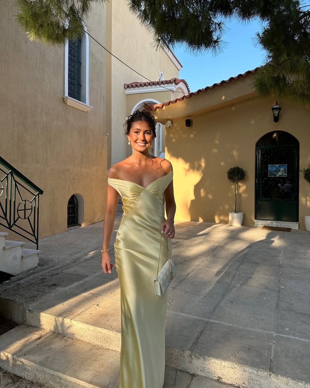 Close-up of the lustrous satin fabric of the Gabrielle gold off-shoulder gown catching the light