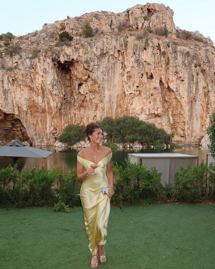 Back view of the Gabrielle gold off-shoulder satin evening dress showing the smooth drape and tailored fit