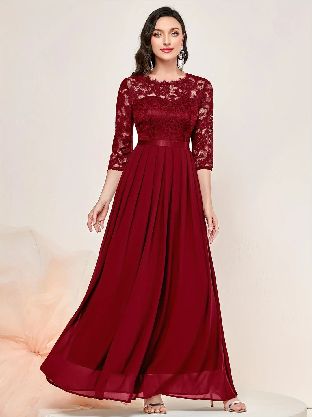 Model in red lace pleated maxi dress at a formal evening setting