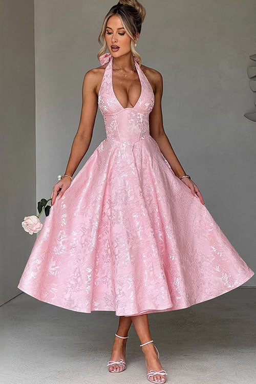 Model wearing a pink V-neck halterneck jacquard maxi dress with a defined waist and flowing flared skirt
