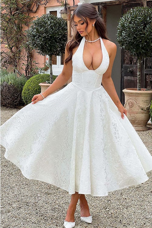 Model posing in a white jacquard halterneck maxi dress highlighting the defined waist and neckline