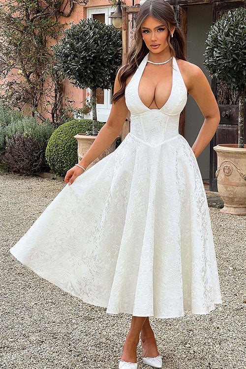 Model in a white halterneck maxi dress with textured jacquard fabric and flowing skirt