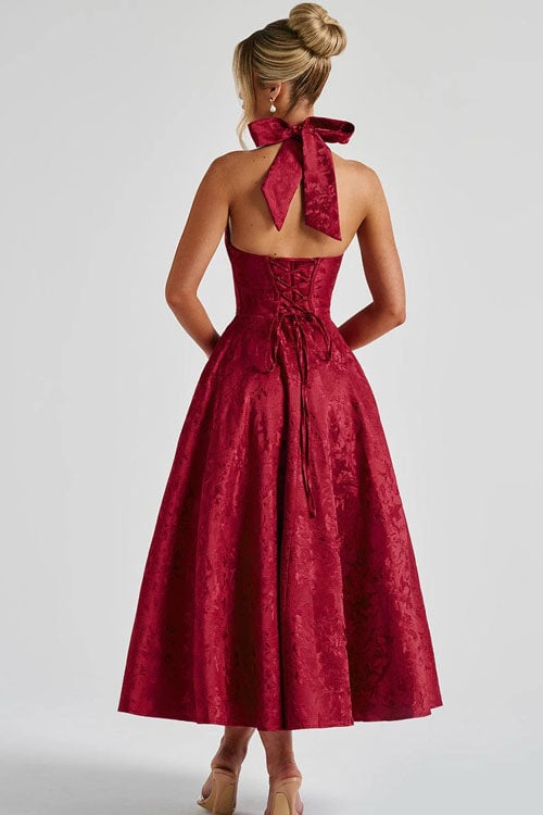 Model in a wine red jacquard halterneck maxi dress with flowing skirt detail