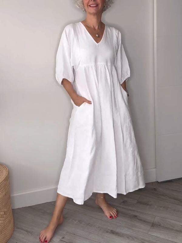 Woman reaching into the side pocket of a white casual midi dress