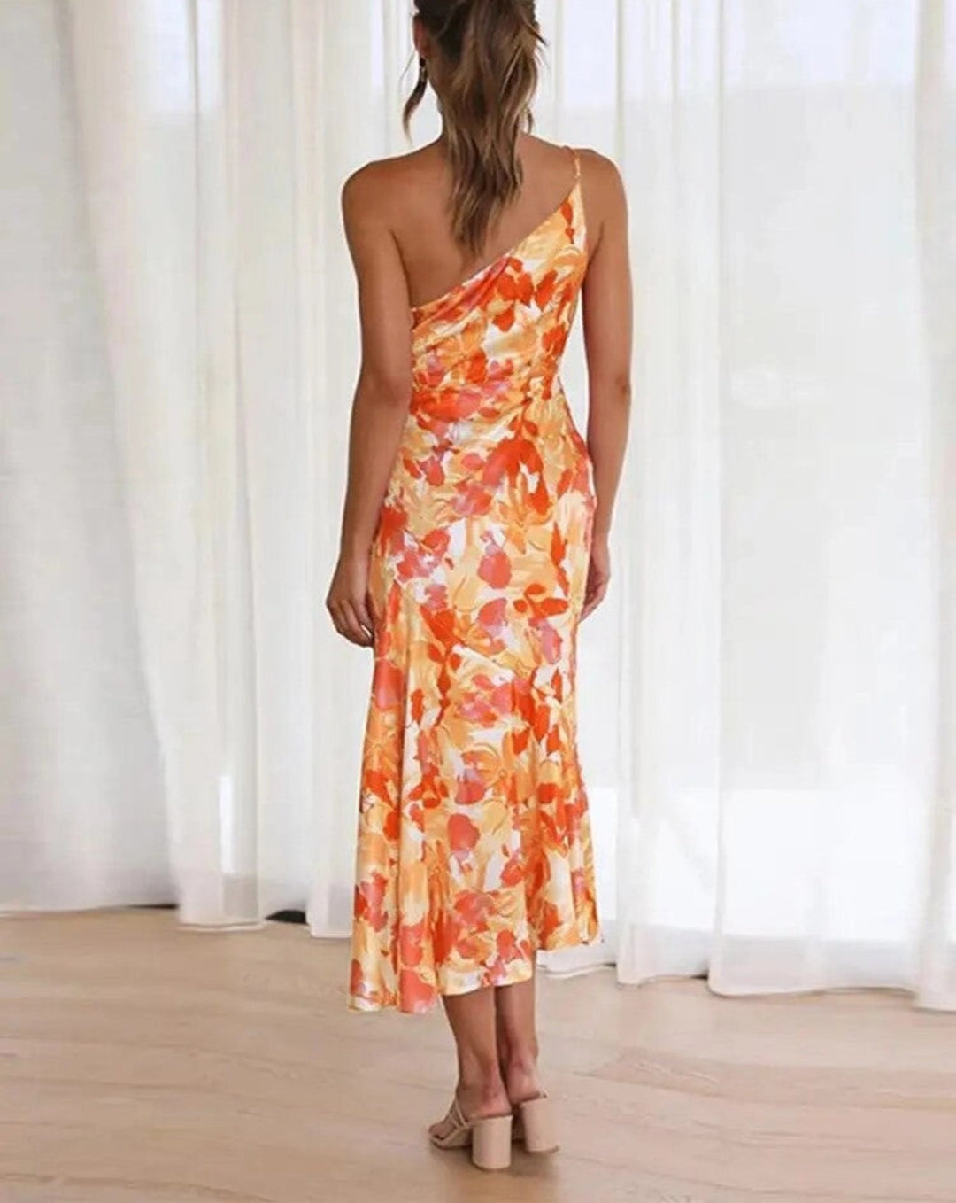 Woman smiling in the Genevieve purple floral asymmetric midi dress at a summer event