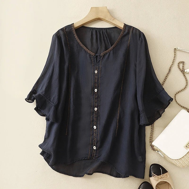 Model wearing navy blue ruffle sleeve blouse styled with light-wash jeans