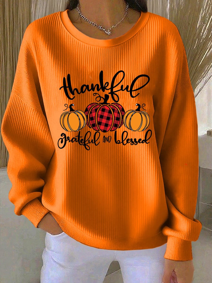 Woman wearing a relaxed orange pullover with a 'Grateful' graphic print, styled for a cozy fall look
