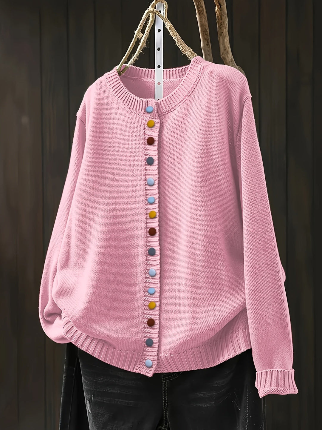 Woman wearing a light pink relaxed-fit cardigan with decorative button accents, front view