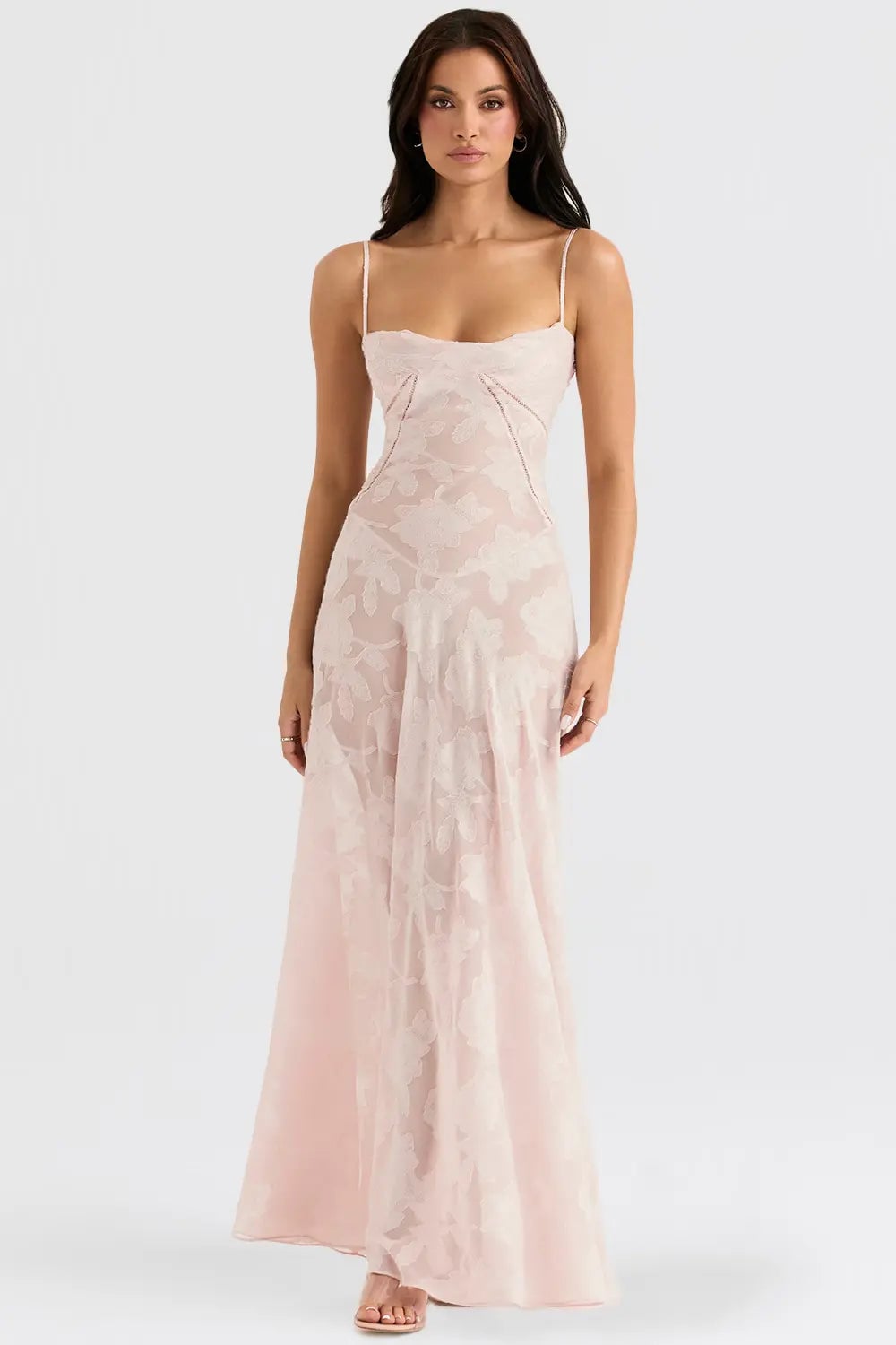 Full-length view of a woman in a long pink summer dress with open back and draped silhouette in natural light
