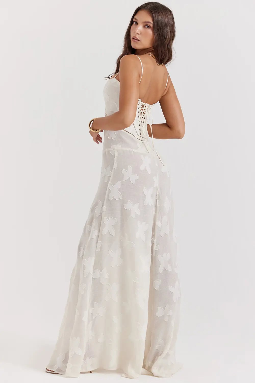 Model smiling in a long white open-back summer dress styled with sandals for a coastal look