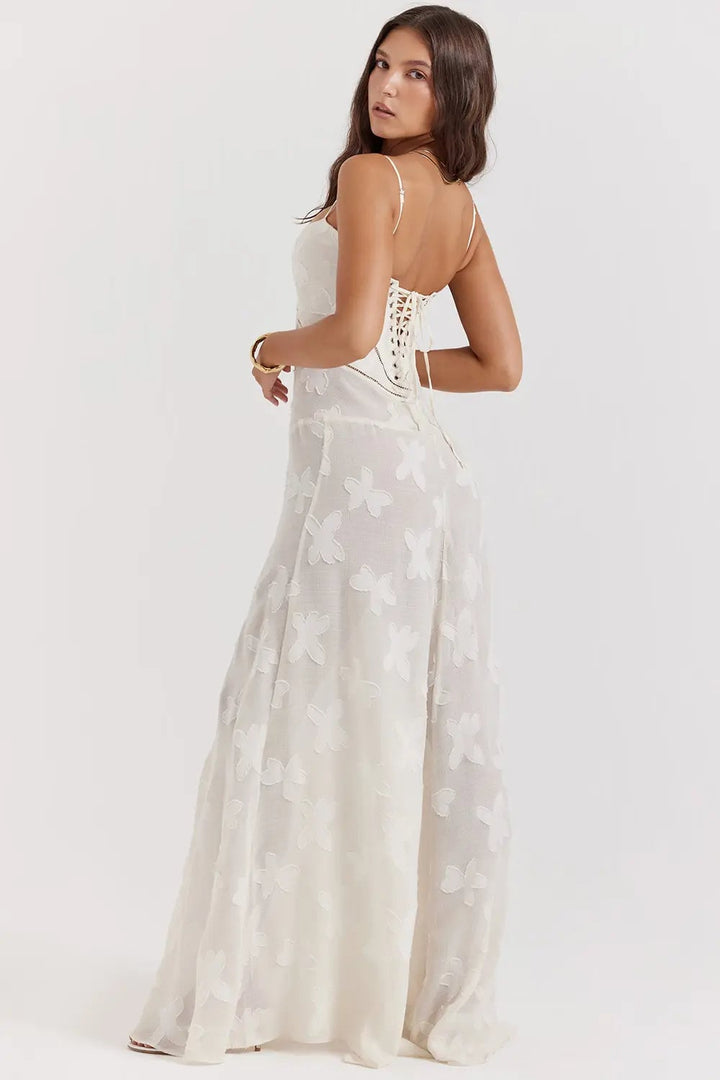 Model smiling in a long white open-back summer dress styled with sandals for a coastal look
