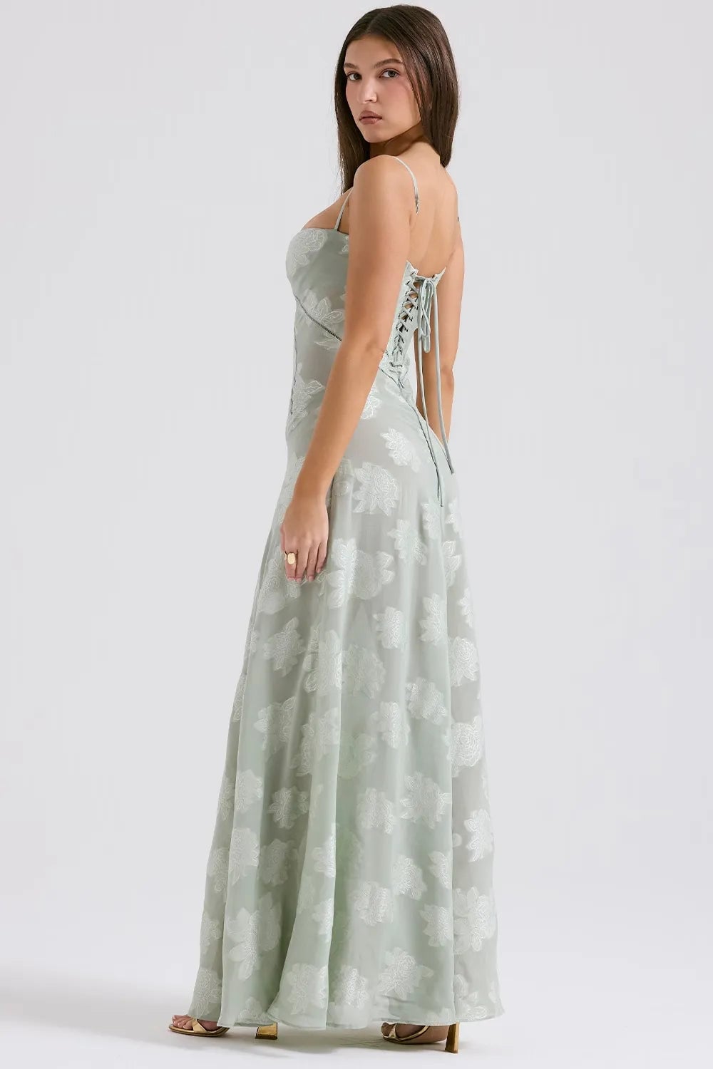 Model wearing a long white summer dress with open back, paired with strappy heels