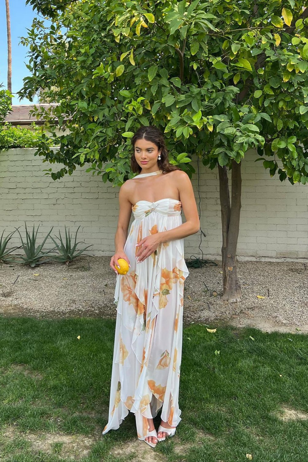 Woman wearing an elegant flowing halter maxi dress with an empire waist in a soft lightweight fabric