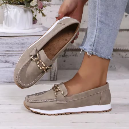 Close-up of gold chain bit hardware detail on black slip-on loafer vamp
