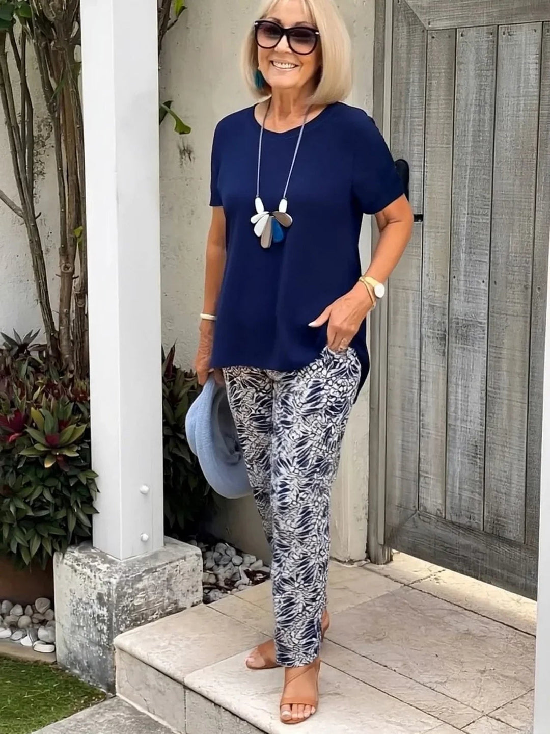 Woman wearing the Florimay Coastal Set in navy blue, featuring a relaxed blouse and matching wide-leg pants, standing in a bright outdoor setting
