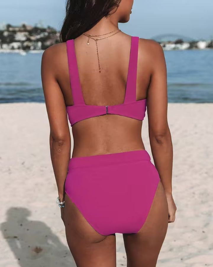 Woman wearing a solid purple high-waist one-piece swimsuit, three-quarter view