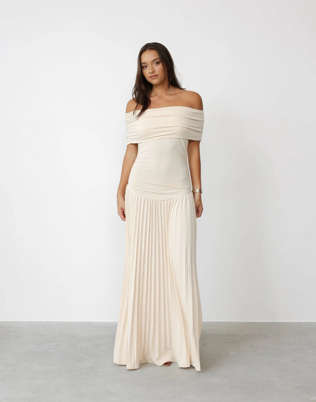 Woman wearing a cream flowy maxi dress outdoors in bright summer sunlight, relaxed silhouette with gentle fabric movement