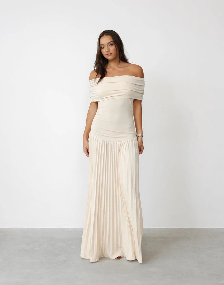 Woman wearing a cream flowy maxi dress outdoors in bright summer sunlight, relaxed silhouette with gentle fabric movement