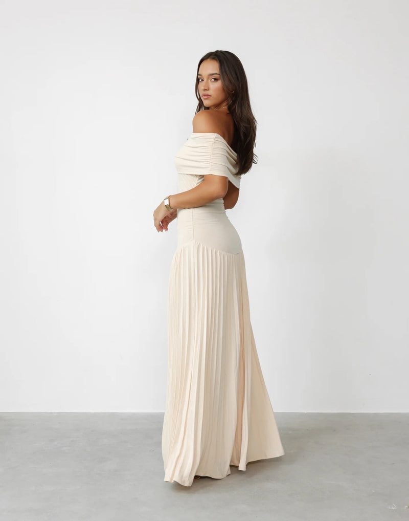 Model in a sky blue full-length maxi dress posing against a light background, showcasing the dress's flowing drape and elegant length