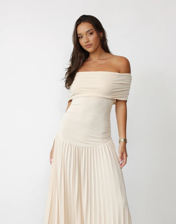 Woman wearing a cream flowy maxi dress at a summer garden party, relaxed and effortlessly styled