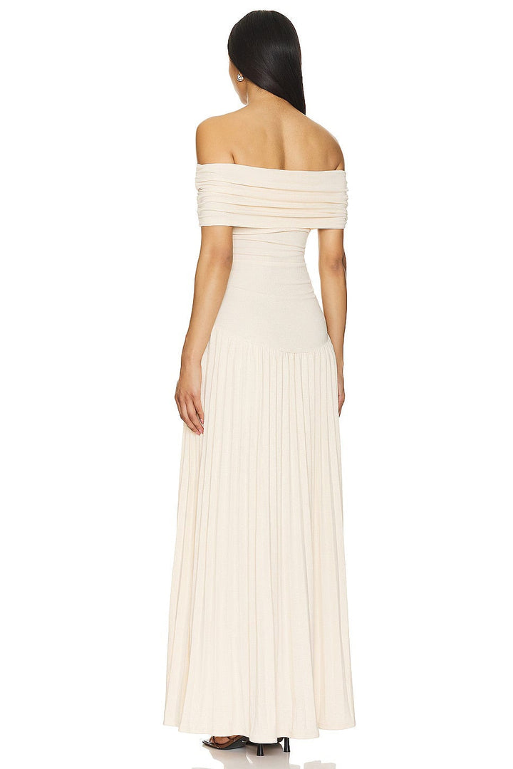 Woman in a cream maxi dress standing in a sunlit field, full-length silhouette displayed beautifully