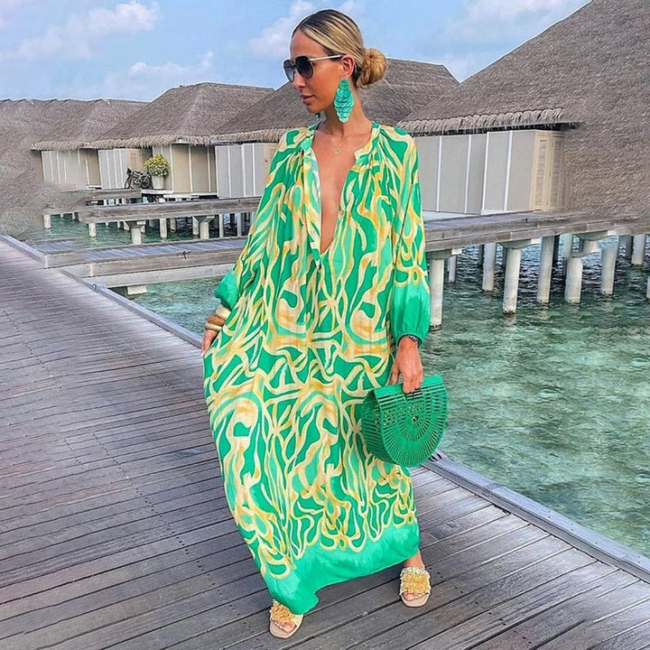Woman wearing a flowy green abstract print maxi kaftan cover-up on the beach