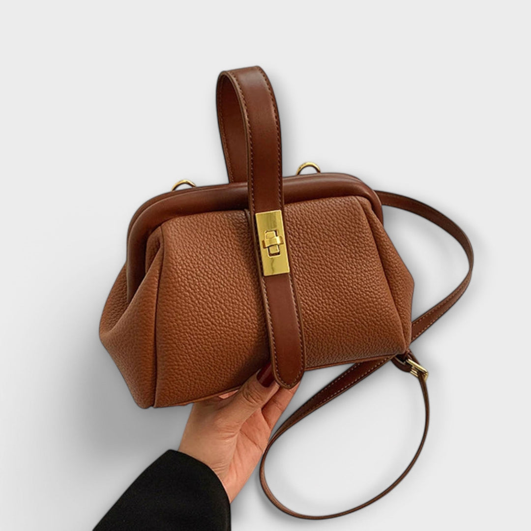 Brown structured mini handbag with golden lock closure on a clean background