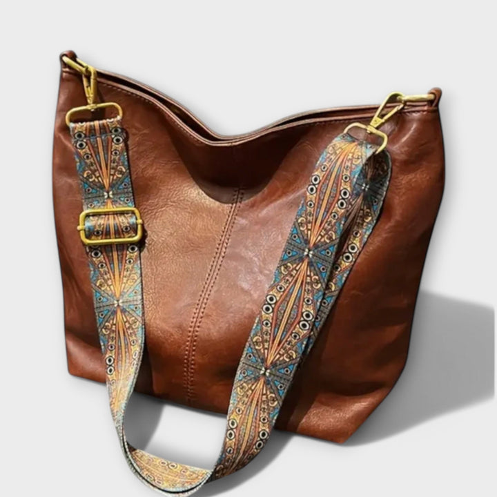 Women's shoulder bag with wide patterned strap in brown, shown from the front against a clean background
