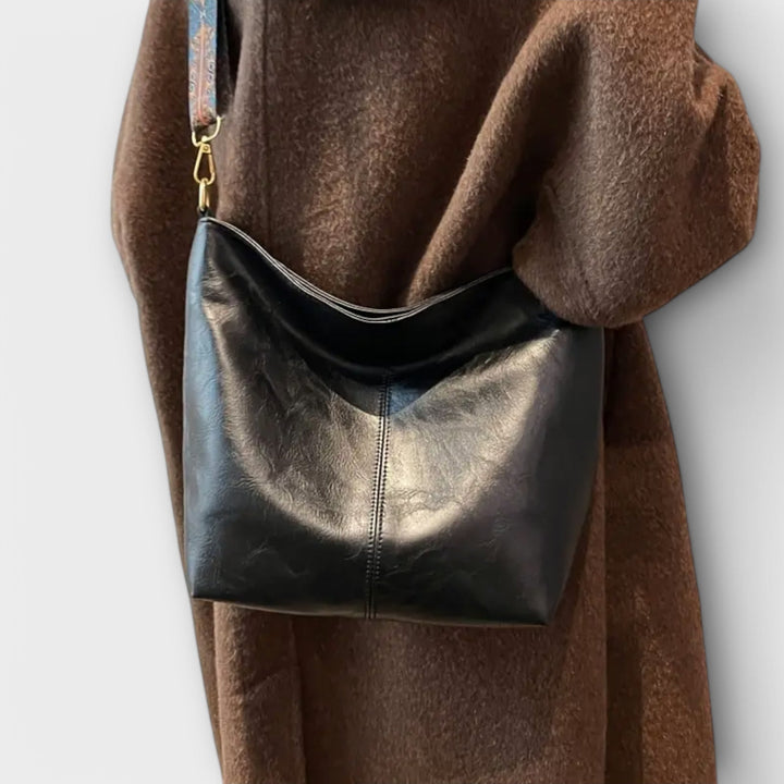 Shoulder bag in black with artistic patterned strap, front view