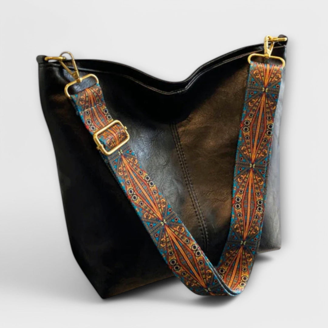 Beige shoulder bag with decorative wide strap displayed on a neutral background