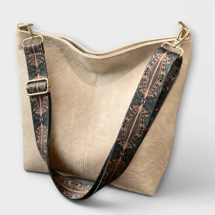 Green shoulder bag with unique patterned strap, styled flat lay view