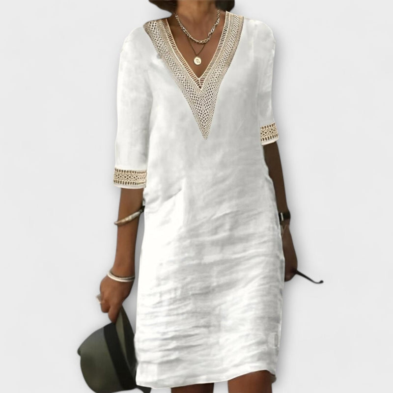 Woman wearing a white crochet boho dress with a flowing silhouette and short sleeves, front view