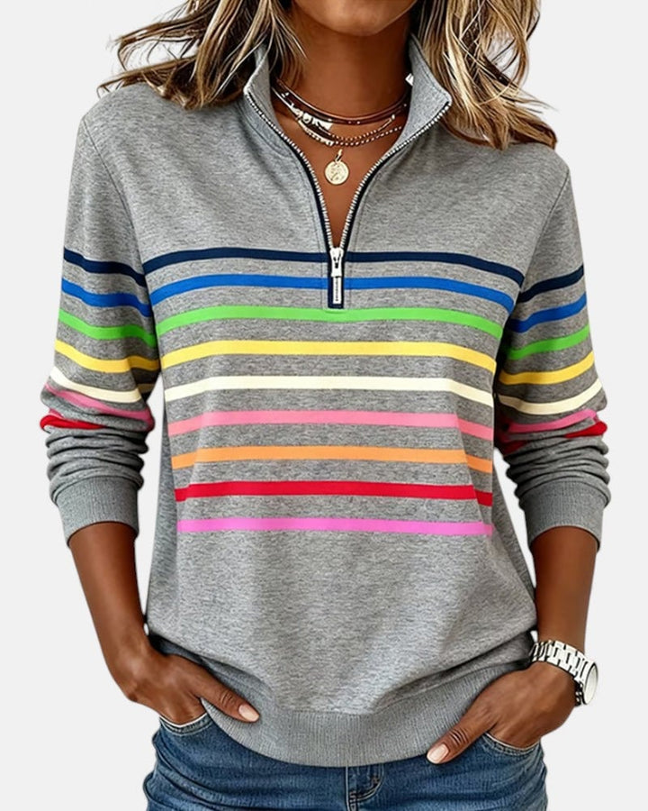 Woman wearing a rainbow striped zip sweatshirt in gray with vertical multicolor stripes and a front zip closure