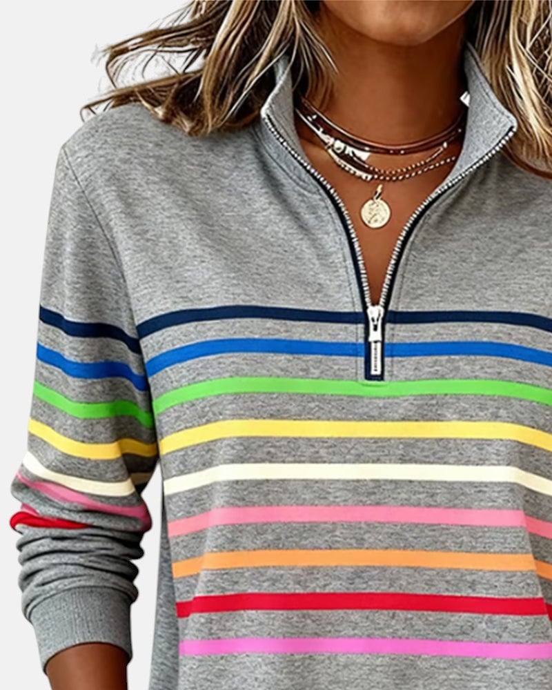 Woman smiling in a red rainbow striped zip sweatshirt with zip partially open