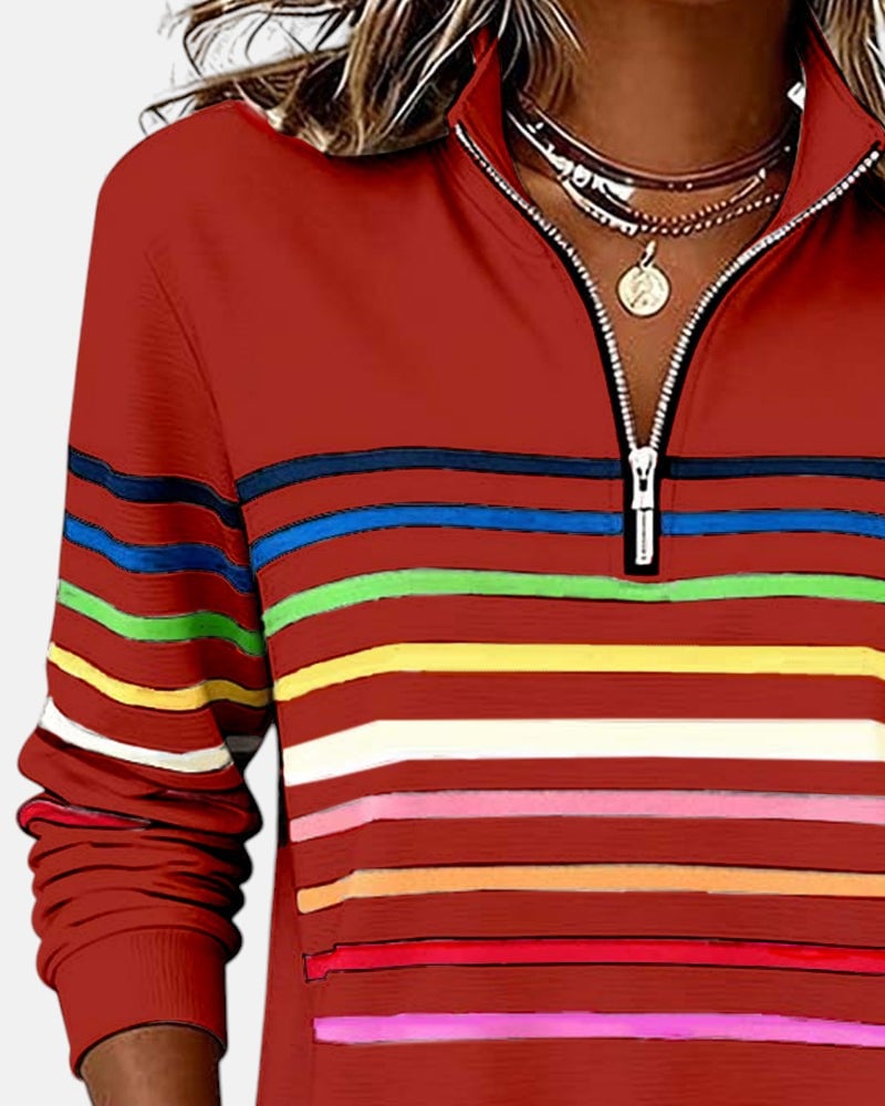 Model wearing navy blue rainbow striped zip sweatshirt in an outdoor setting