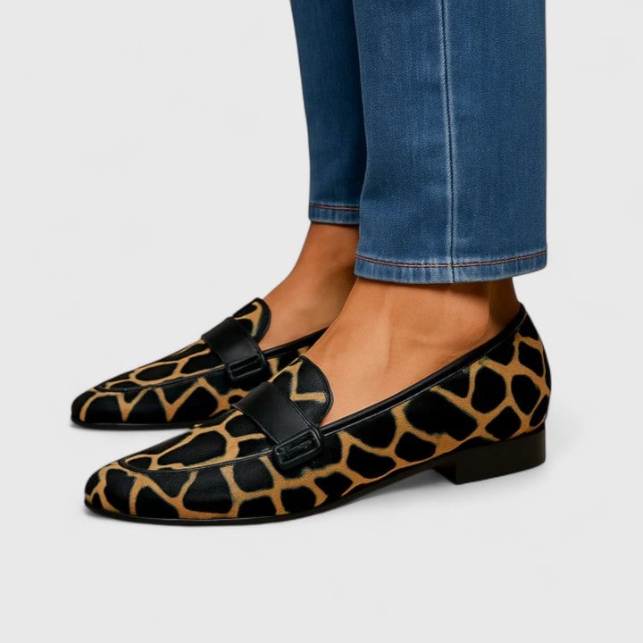 Black and gold women's loafers with a sleek minimalist silhouette and gold-tone hardware detail, shown on a clean white background