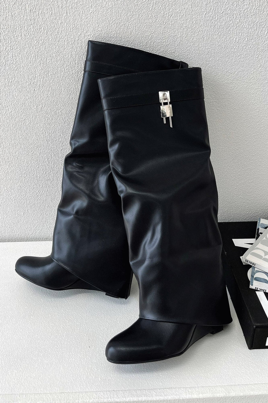 Model wearing black knee-high boots paired with a casual everyday outfit, side view