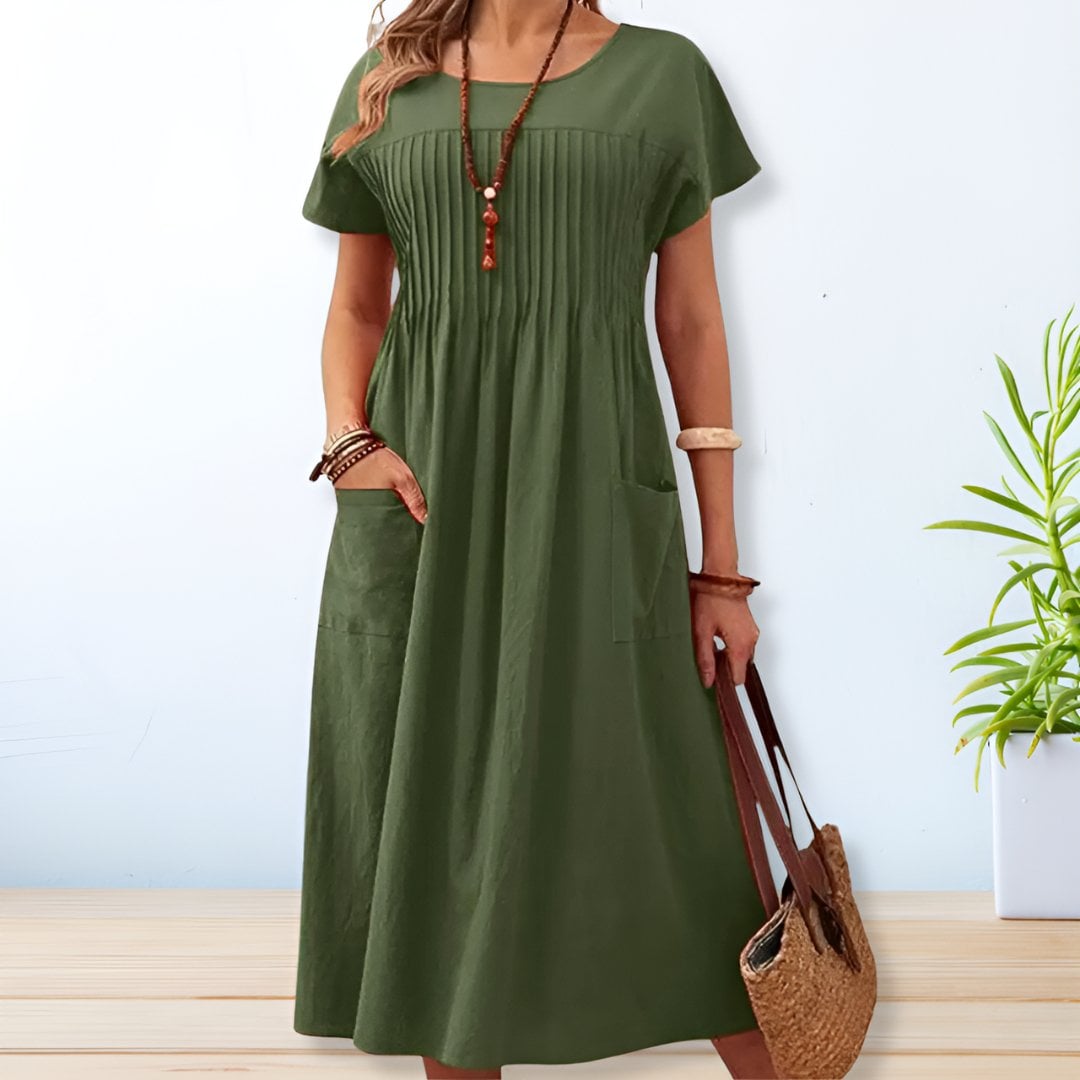 Woman wearing a relaxed fit mid-length day dress in a soft color, standing in a bright outdoor setting