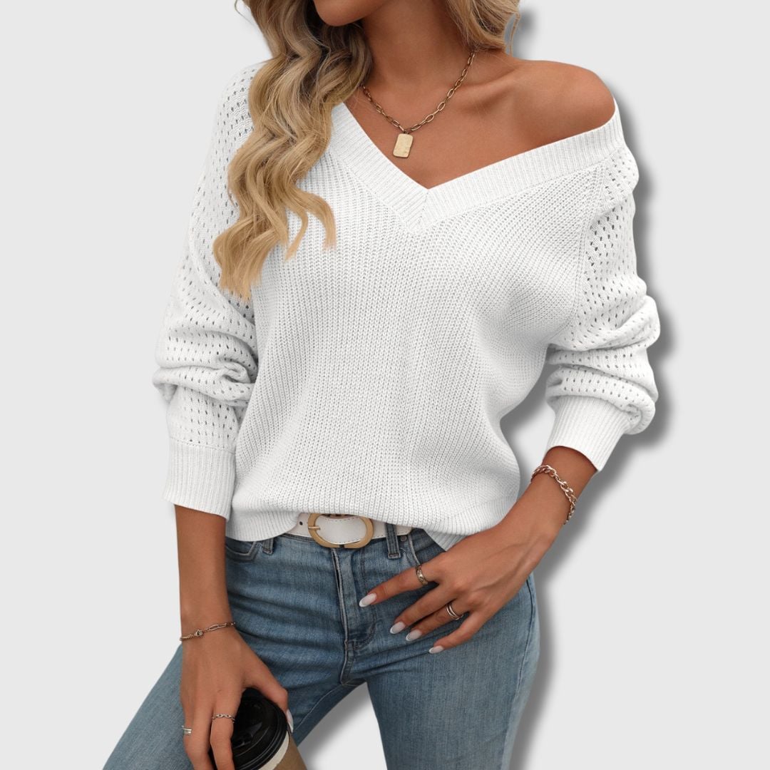 Lifestyle shot of a woman wearing a white V-neck sweater paired with jeans for a casual chic outfit